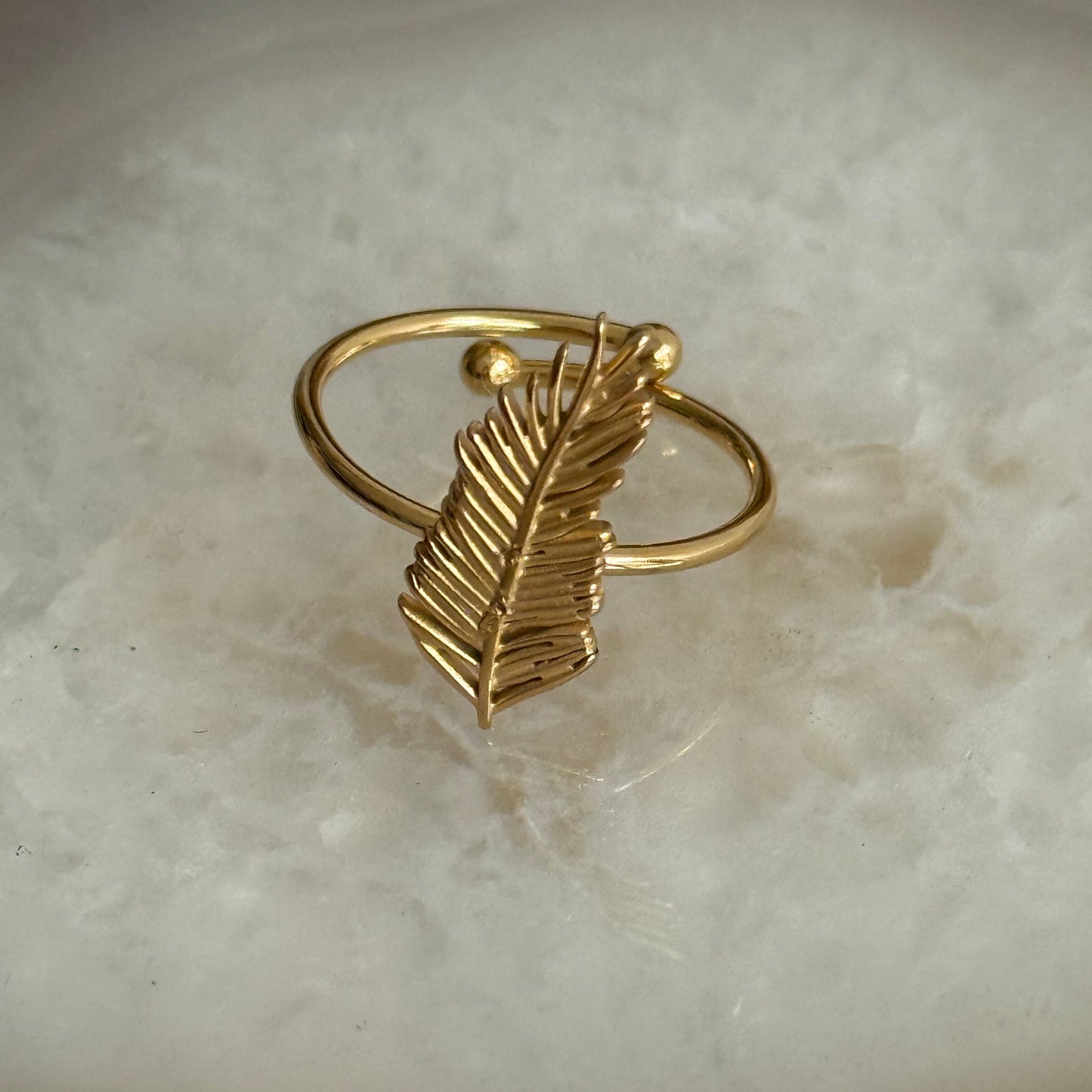Gold leaf-shaped ring on a marble surface