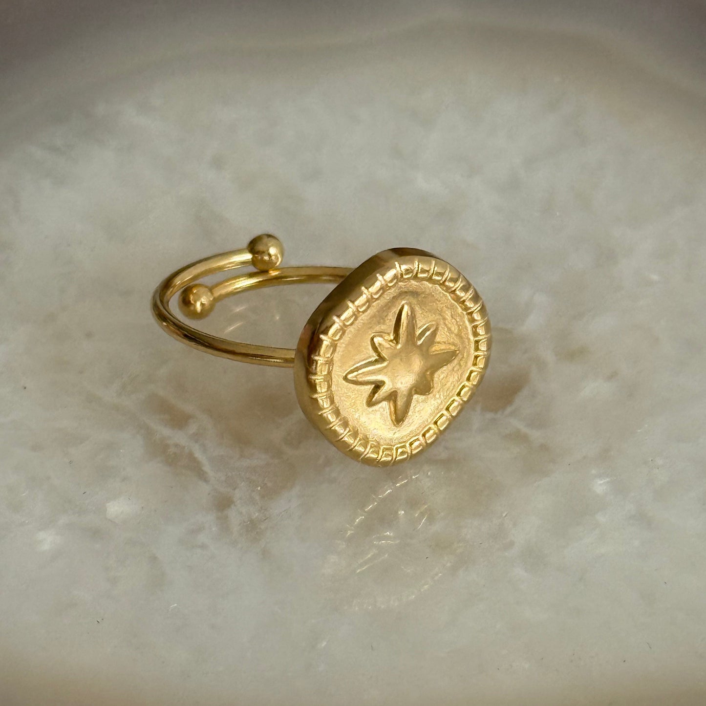 Gold ring with star design on a marble surface