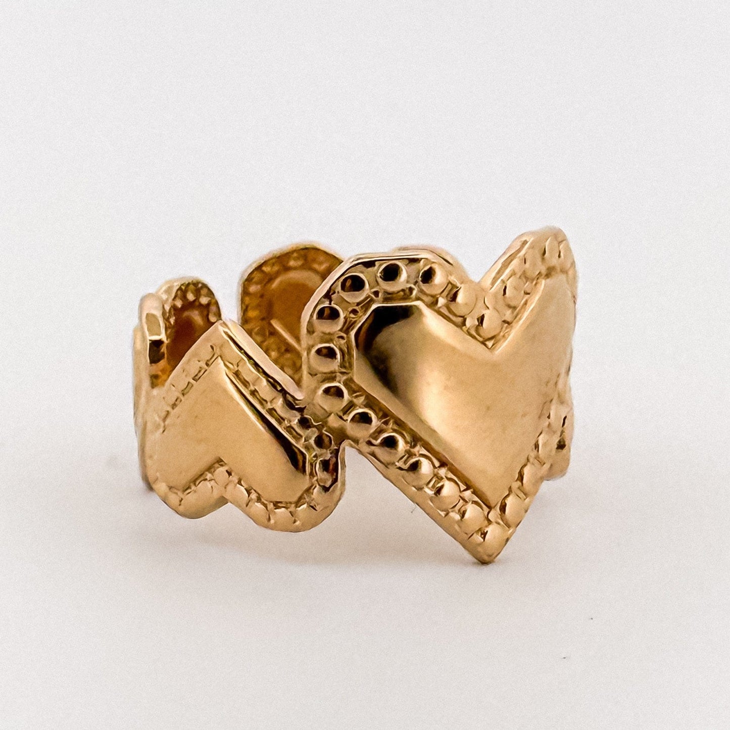 Gold ring with heart design on a white background
