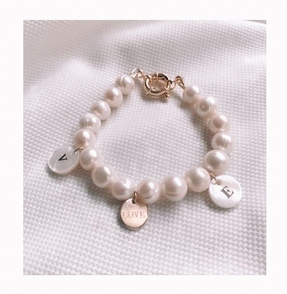 Golden initial engraved in a shell round disk