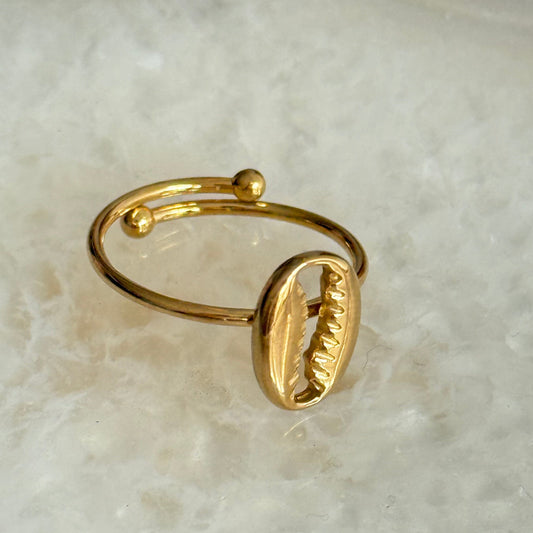 Gold ring with a shell design on a light marble background