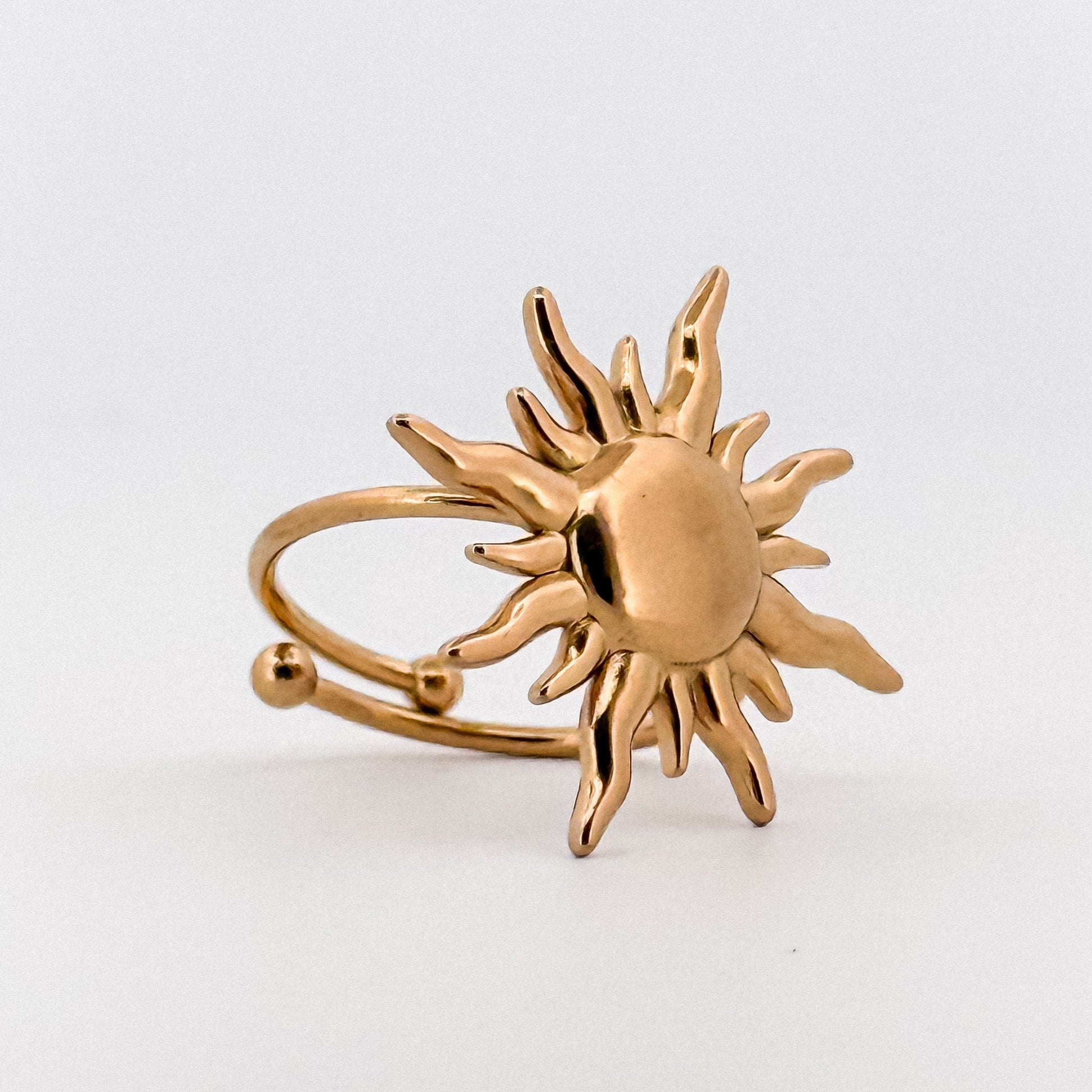 Gold sun-shaped ring on a white background