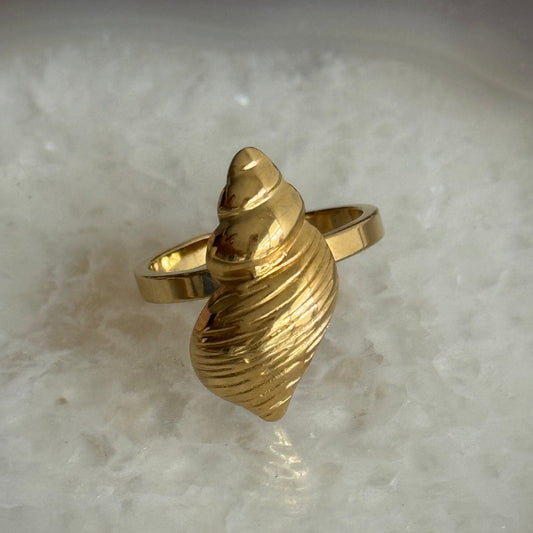 Gold shell-shaped ring on a marble surface