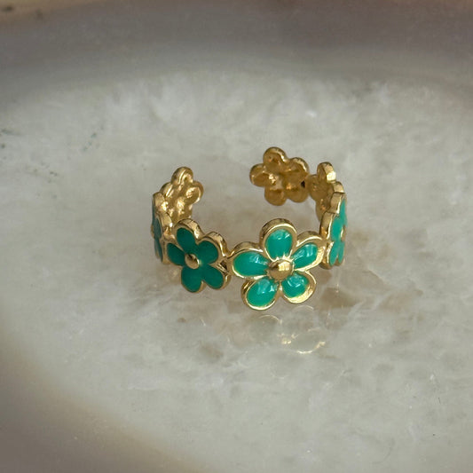 Gold ring with green gemstones on a light background