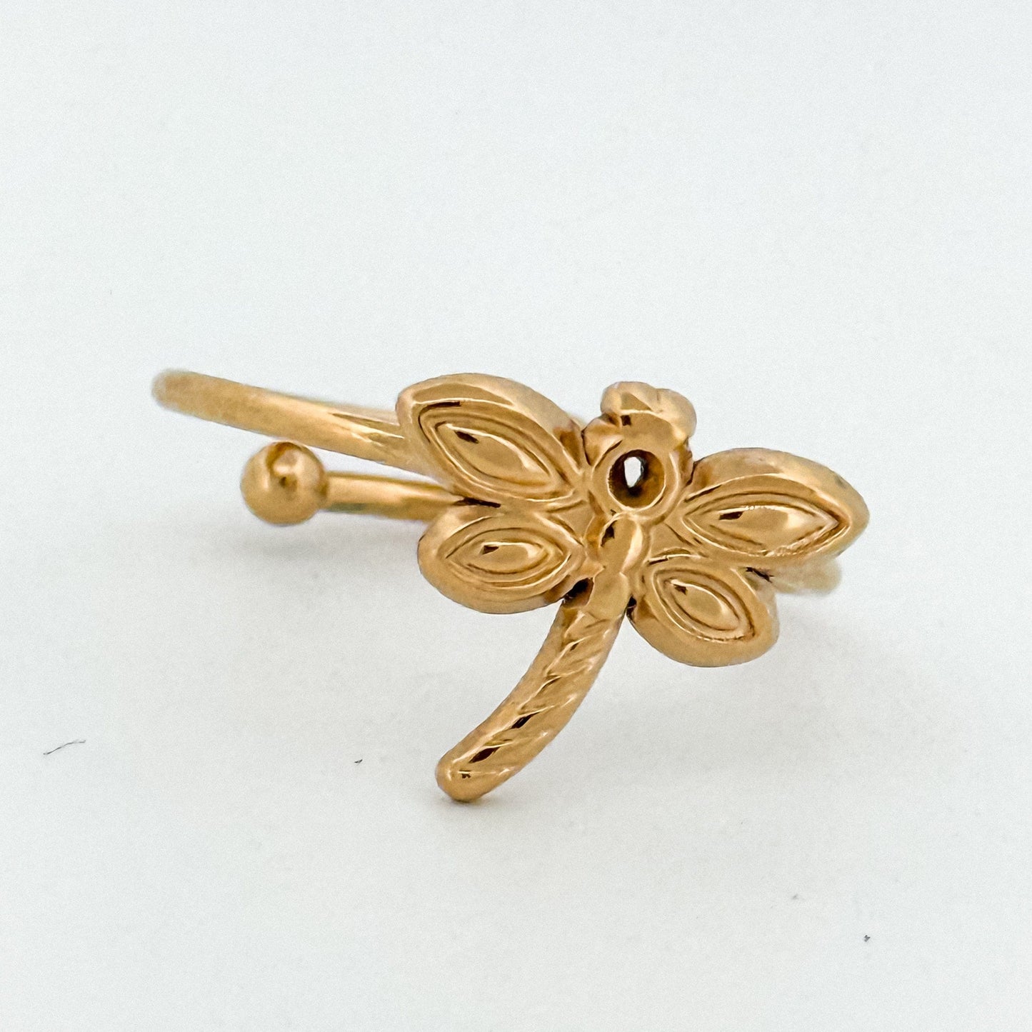 Gold dragonfly-shaped ring on a white background