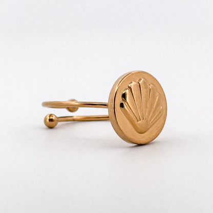 Gold ring with a shell design on a white background