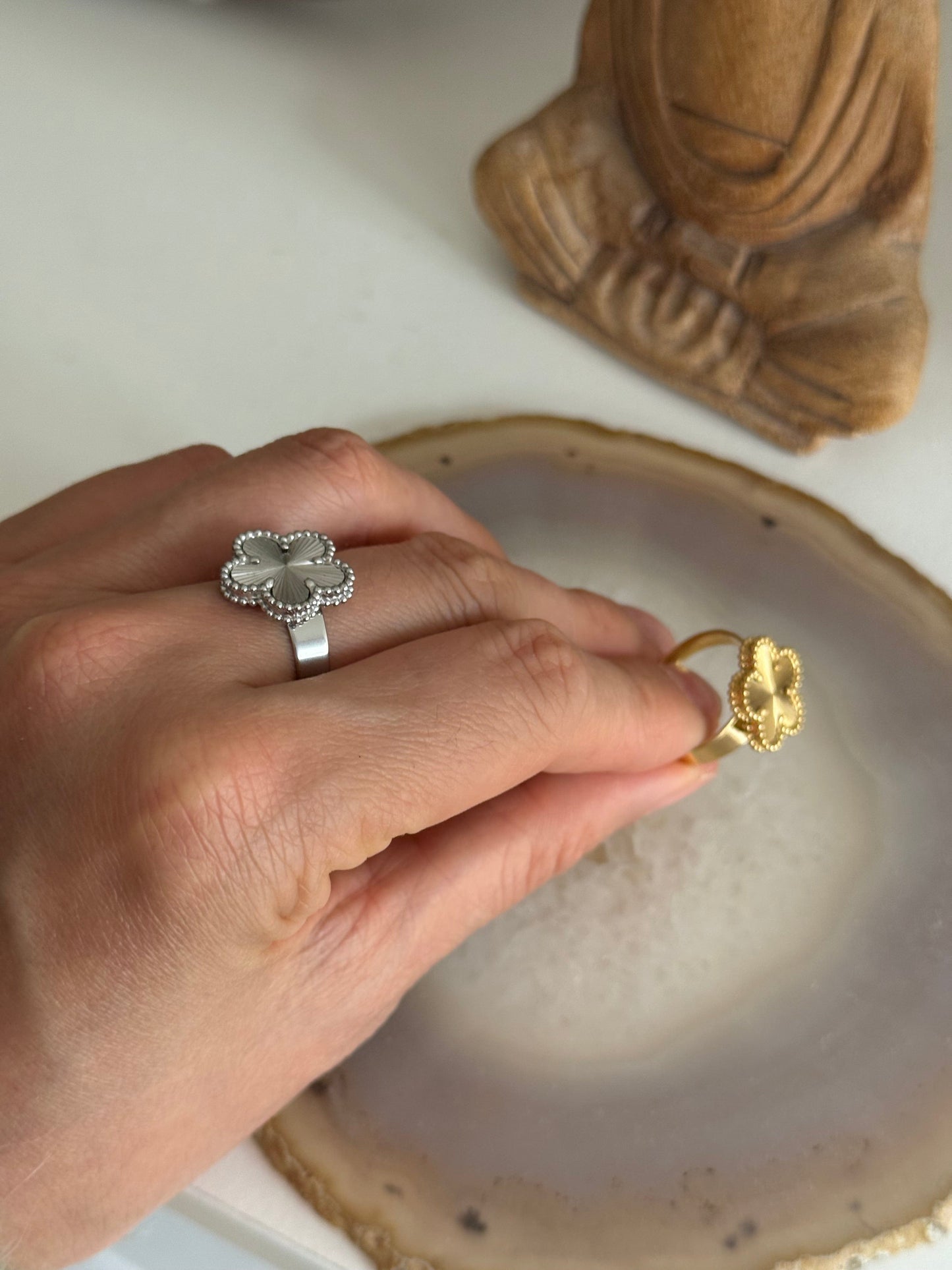 Hand holding a gold ring over a textured surface with a wooden object in the background