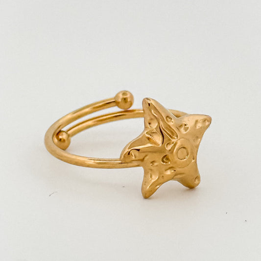 Gold ring with a star-shaped design on a light gray background