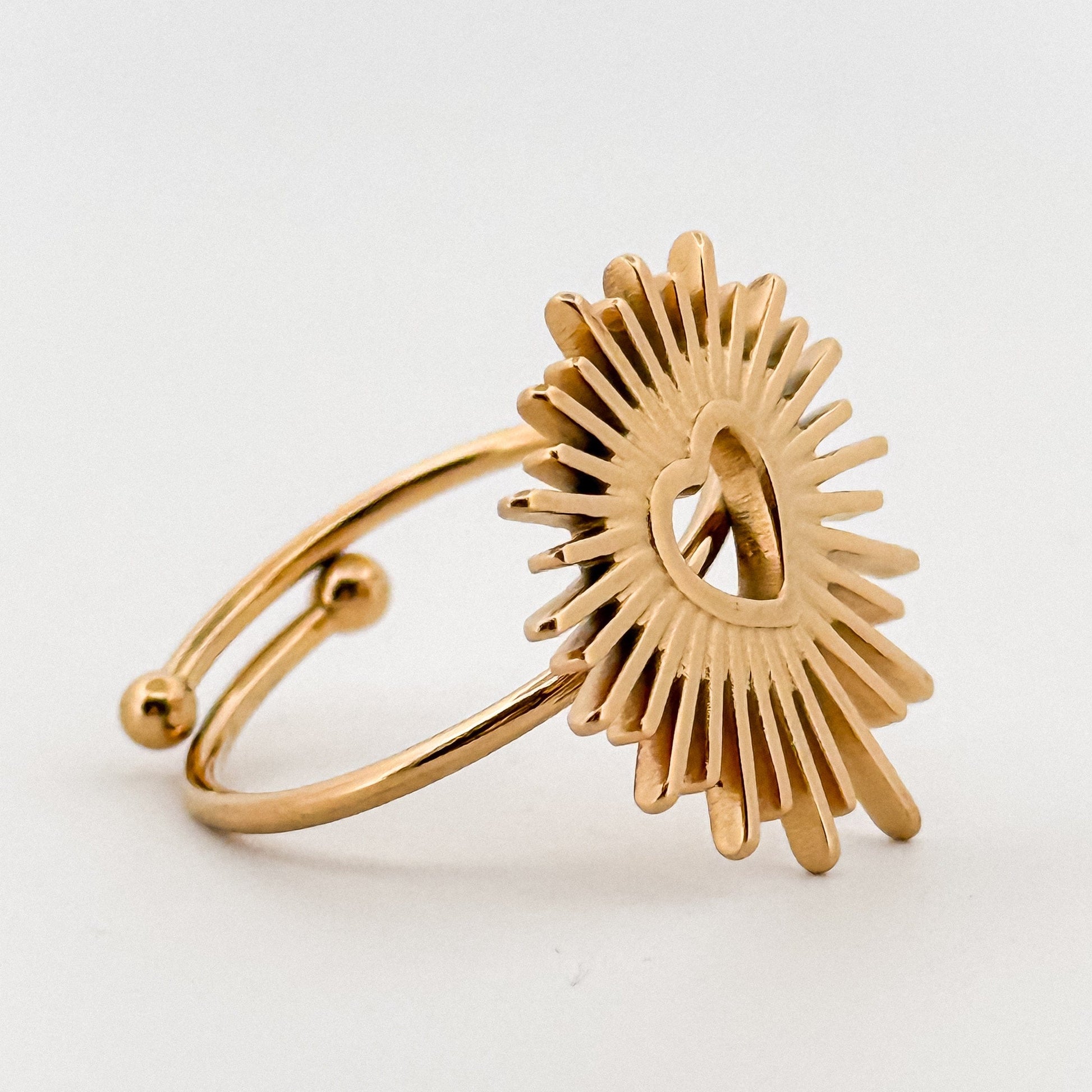 Gold ring with a sunburst design on a white background