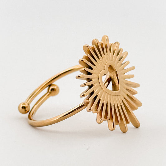 Gold ring with a sunburst design on a white background