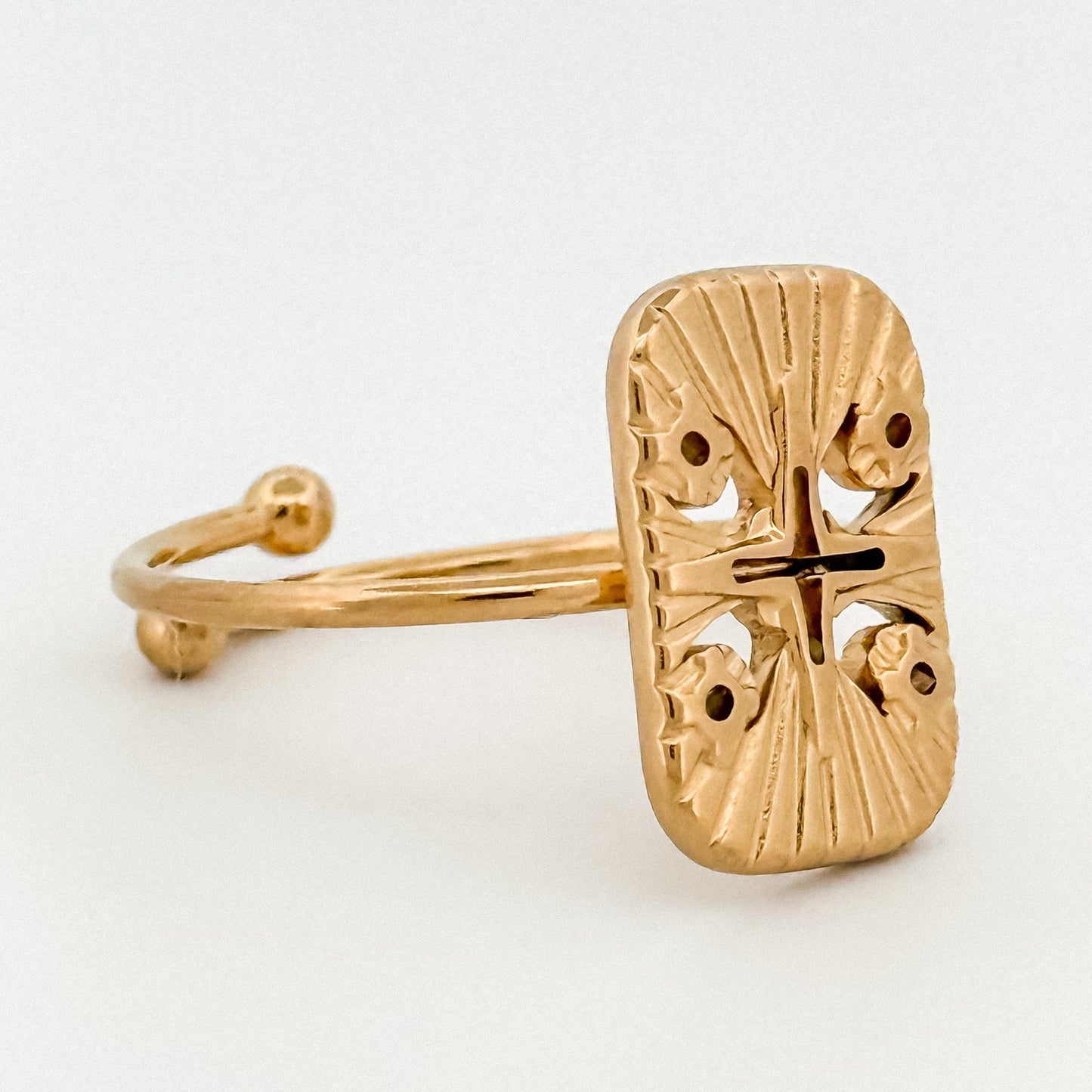 Gold ring with intricate design on a white background