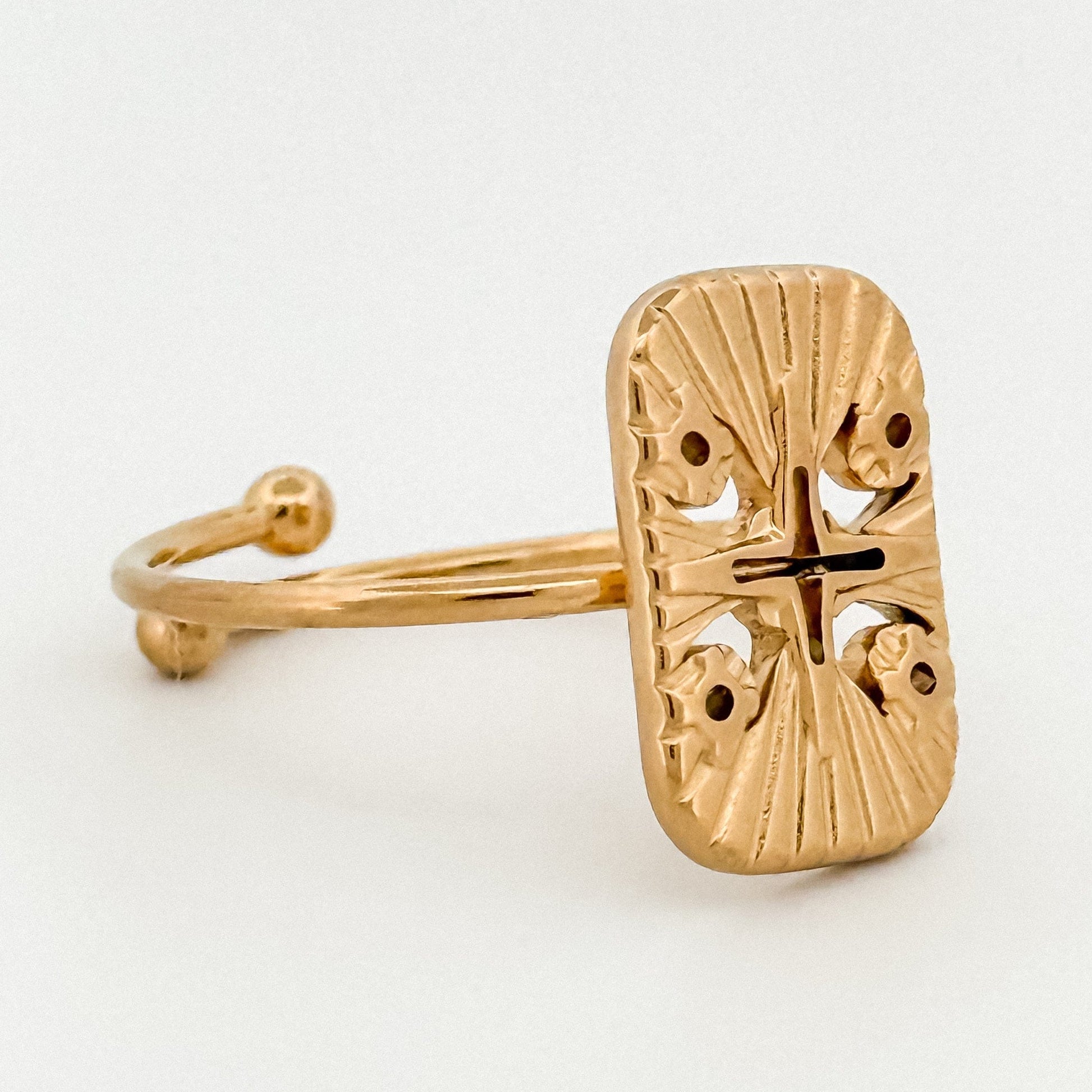 Gold ring with intricate design on a white background