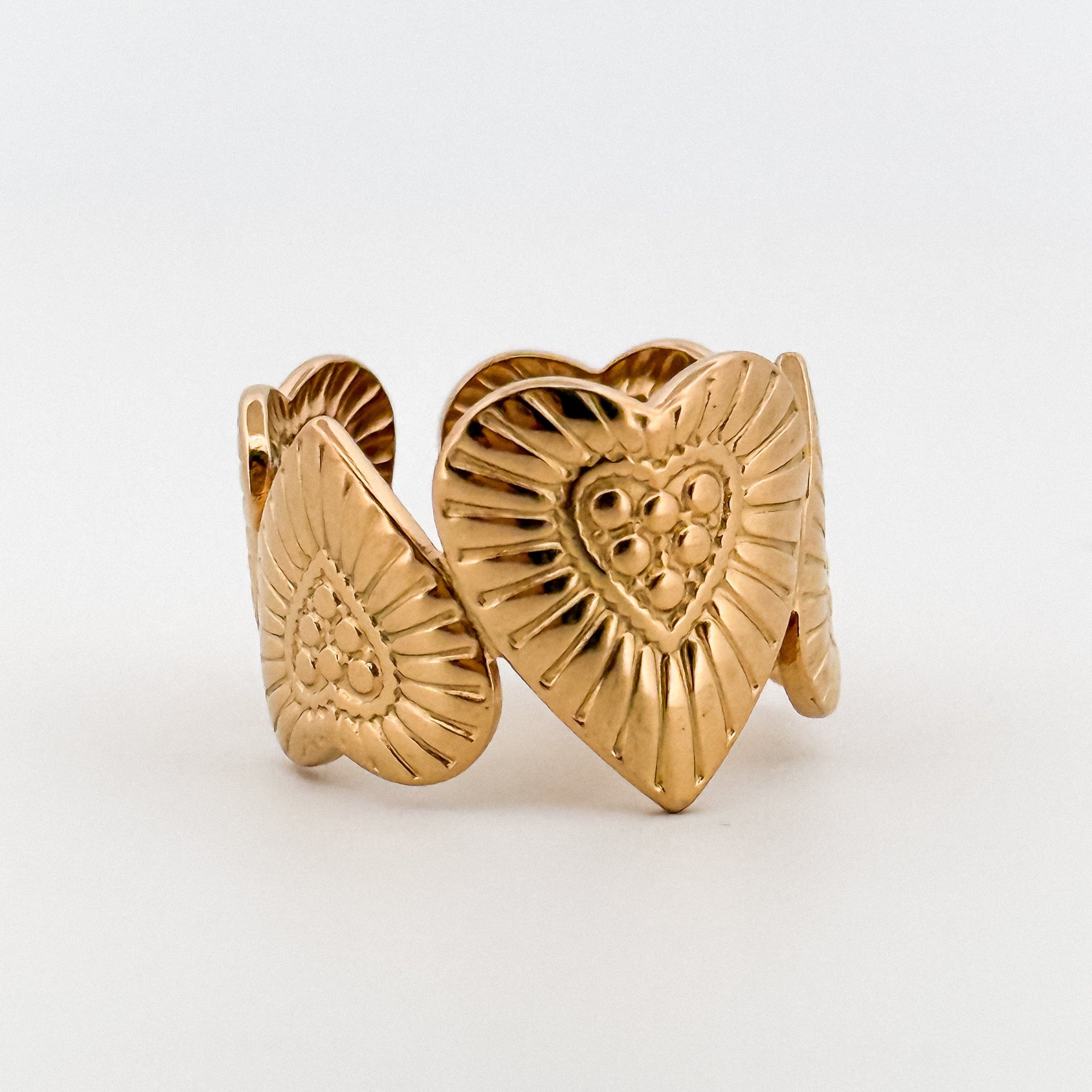 Gold heart-shaped earrings with intricate designs on a white background