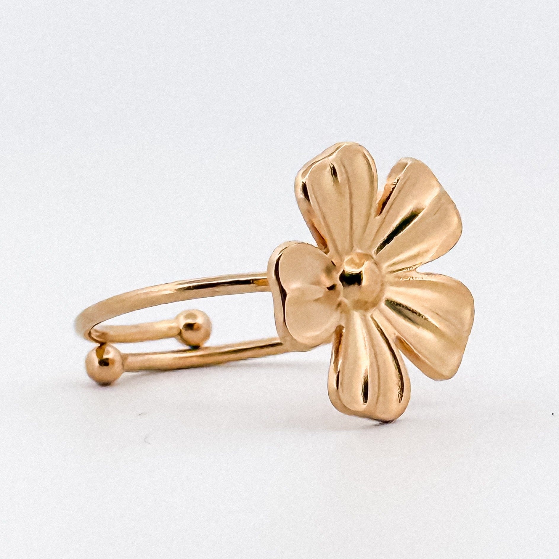 Gold flower-shaped ring on a white background