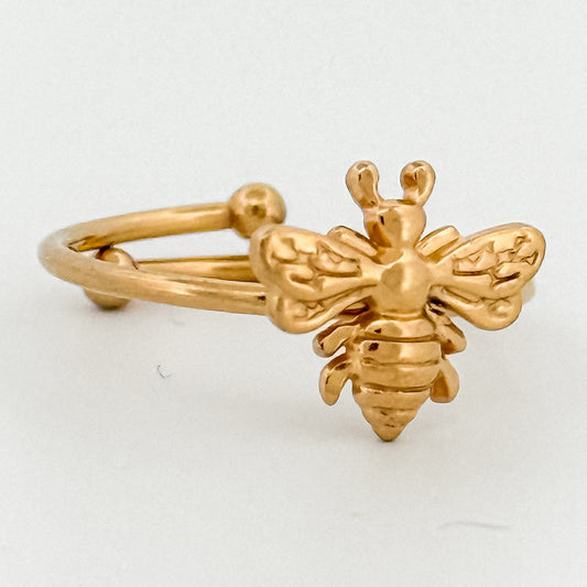 Gold bee-shaped ring on a white background