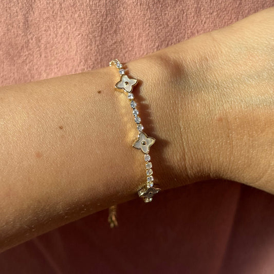 Gold bracelet with flower-shaped charms made of mother pearl on a wrist