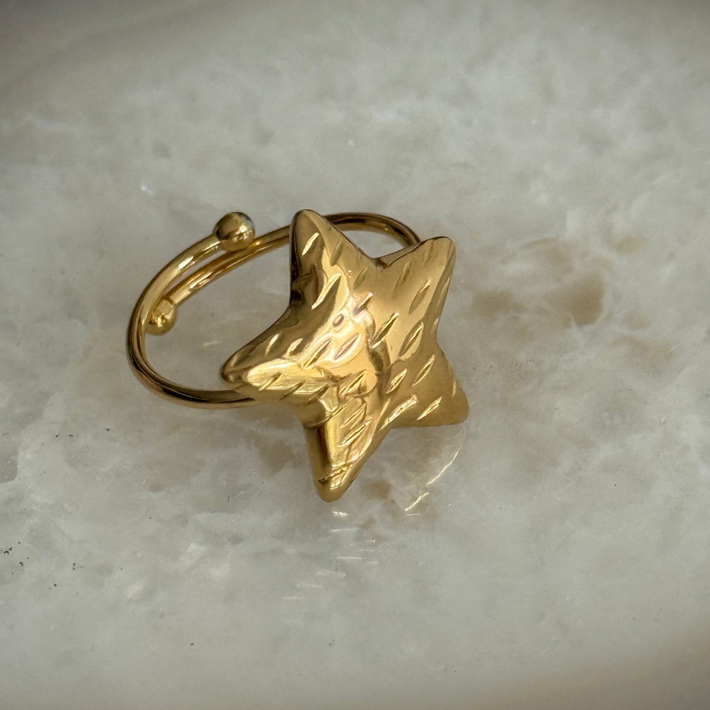Gold star-shaped ring on a light marble background