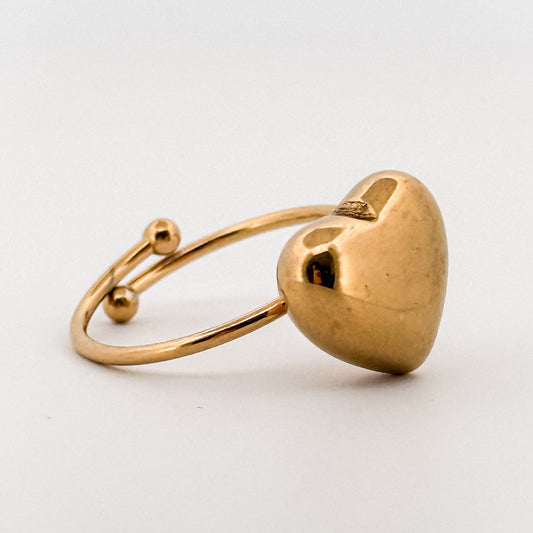 Gold heart-shaped ring on a light gray background