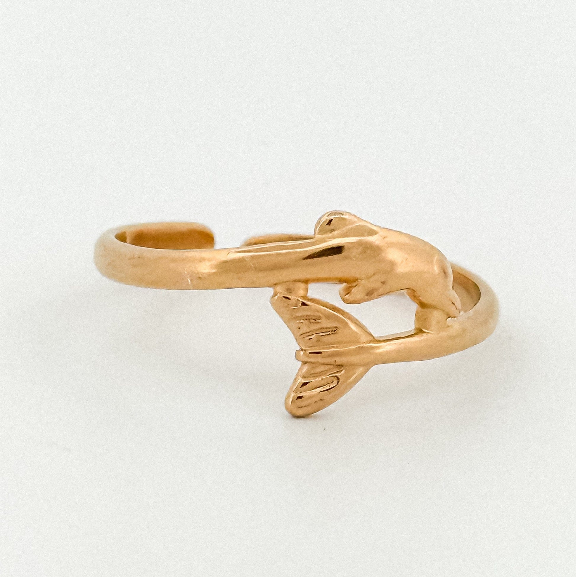 Gold dolphin-shaped ring on a light gray background