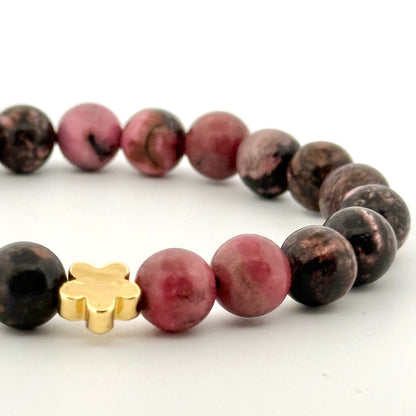 Bracelet with purple and black beads and a gold clasp on a white background