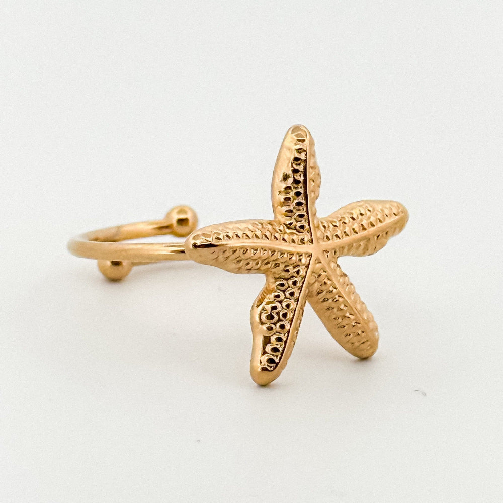 Gold starfish ring on a white background
