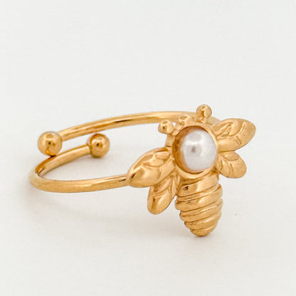Gold bee-shaped ring with a pearl on a light gray background