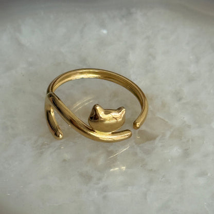 Gold ring with a small cat design on a marble surface