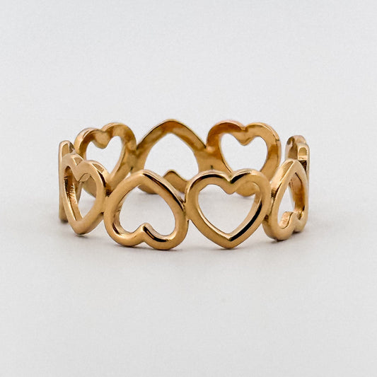 Gold ring with heart designs on a light gray background