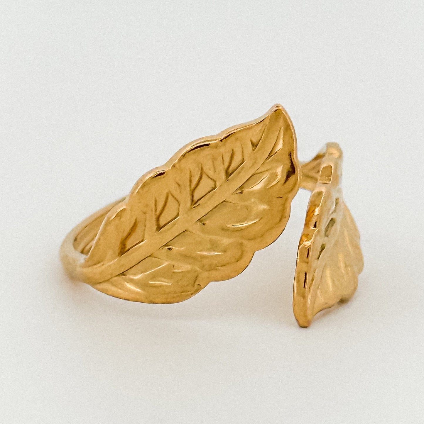 Gold leaf-shaped ring on a light gray background