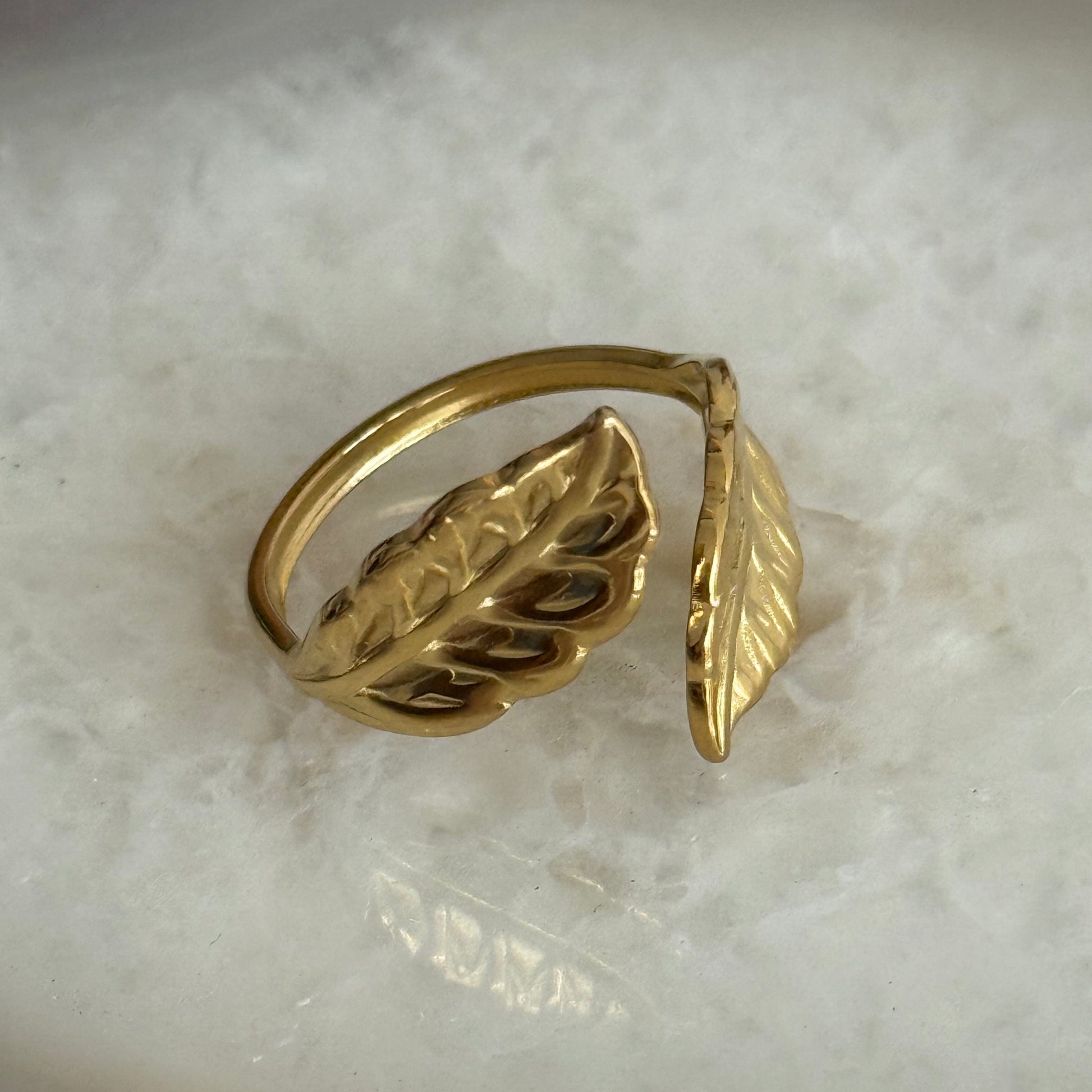 Gold leaf-shaped ring on a marble surface