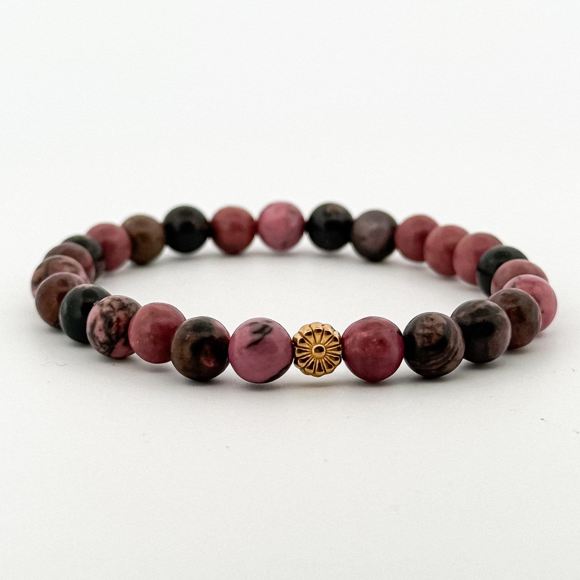 Beaded bracelet with pink and brown beads and a gold center piece on a white background