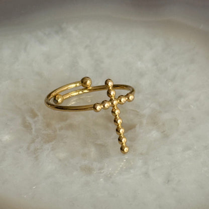 Gold ring with a cross design on a marble surface