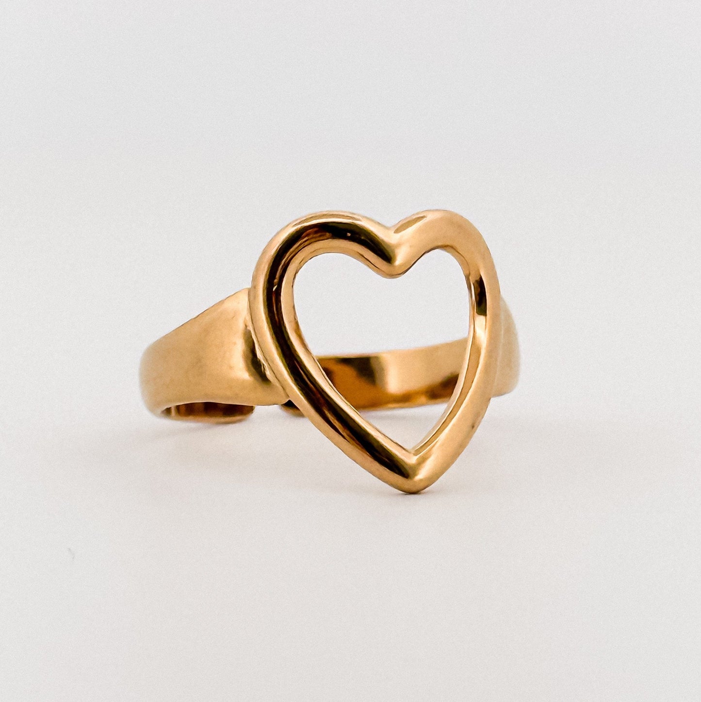 Gold heart-shaped ring on a light gray background