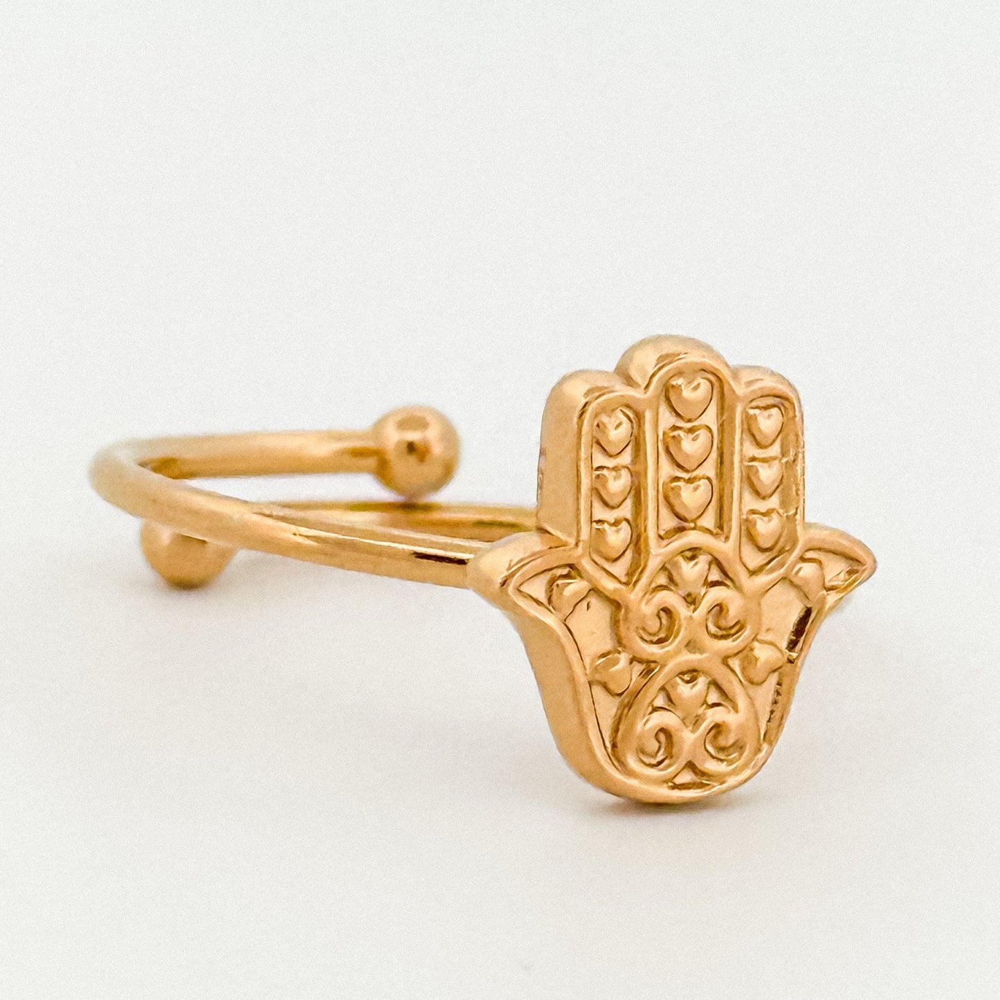 Gold Hamsa hand ring on a light gray background