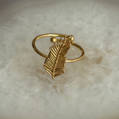 Gold leaf-shaped ring on a marble surface