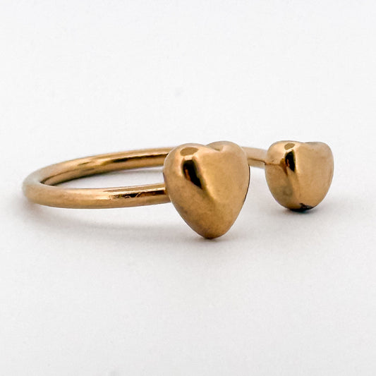 Gold ring with heart-shaped ends on a white background