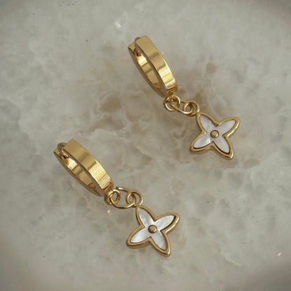 Gold earrings with floral designs on a textured surface