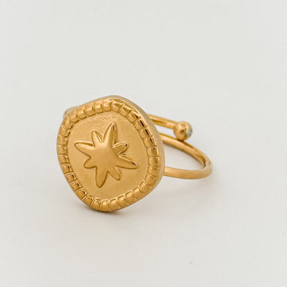 Gold ring with star design on a light gray background