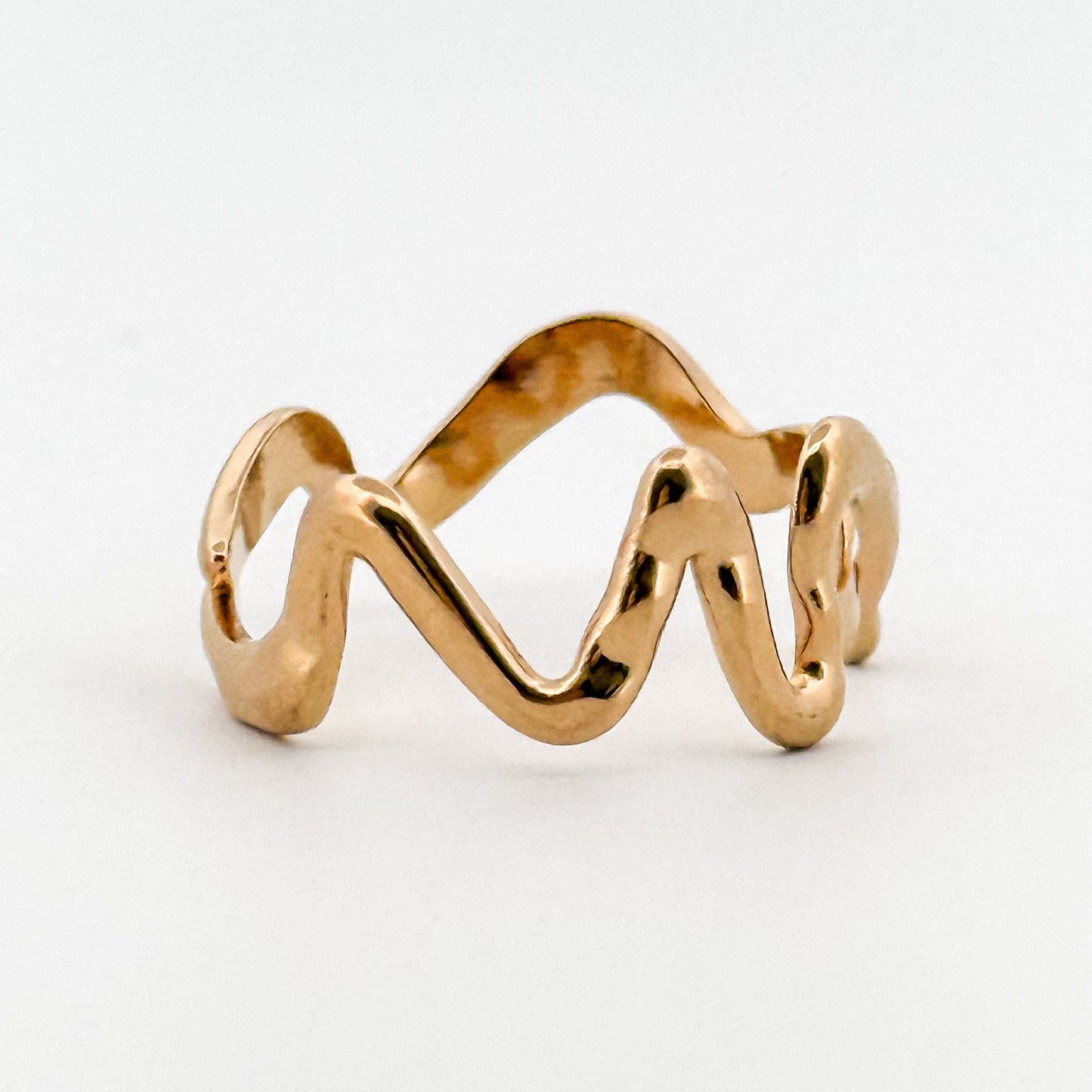 Gold ring with a wavy design on a white background