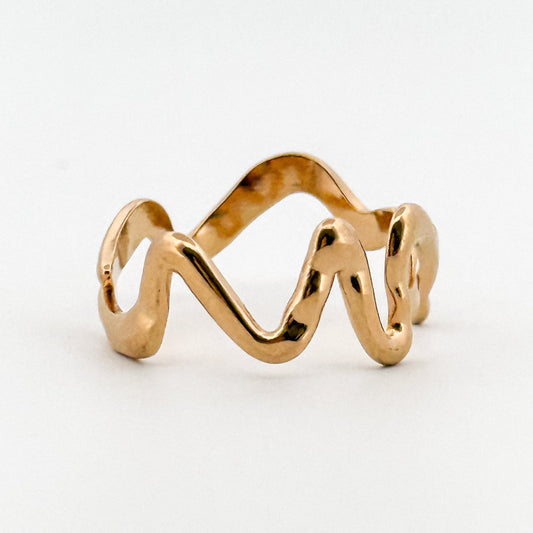 Gold ring with a wavy design on a white background