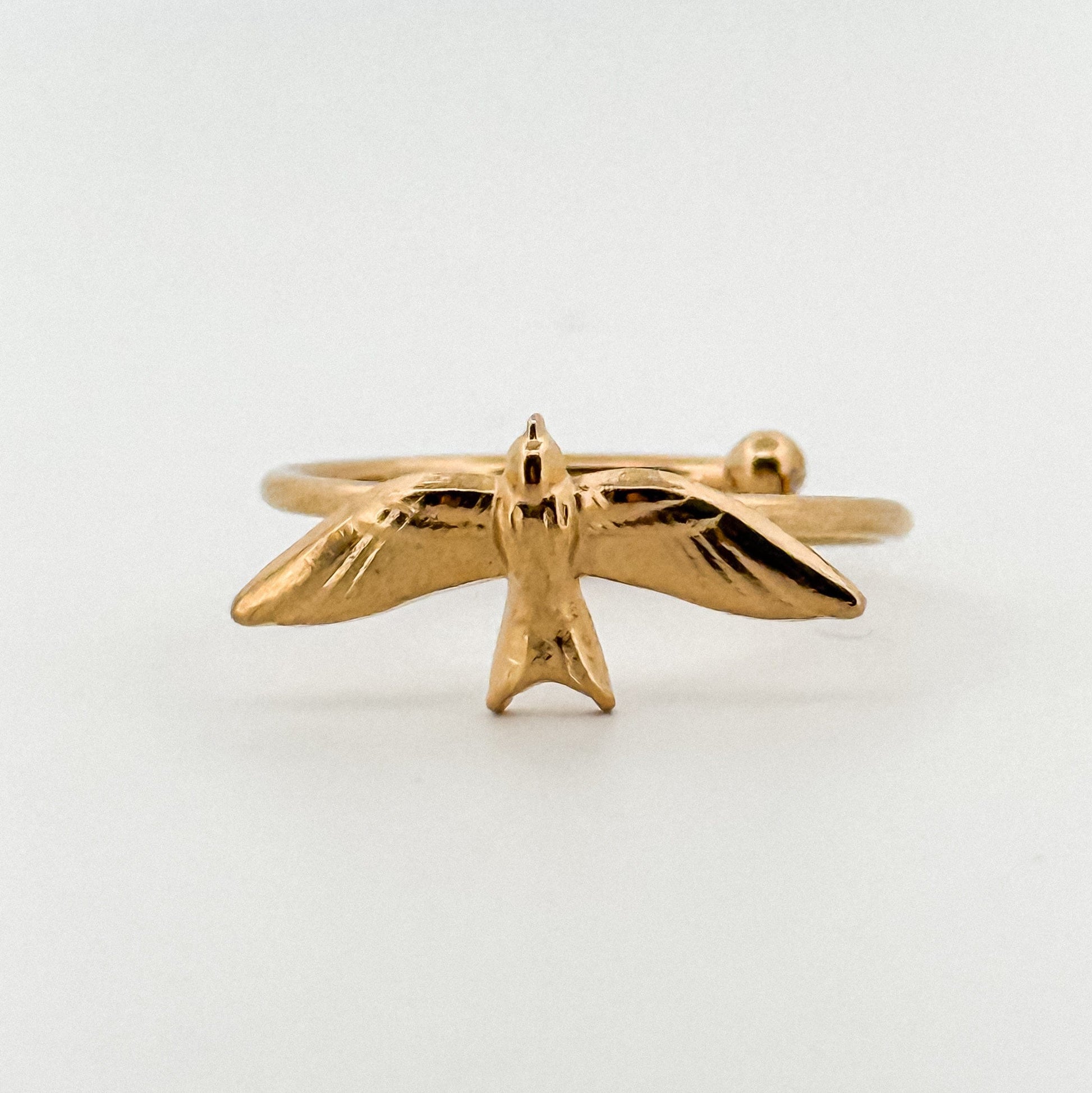 Gold bird-shaped ring on a light background