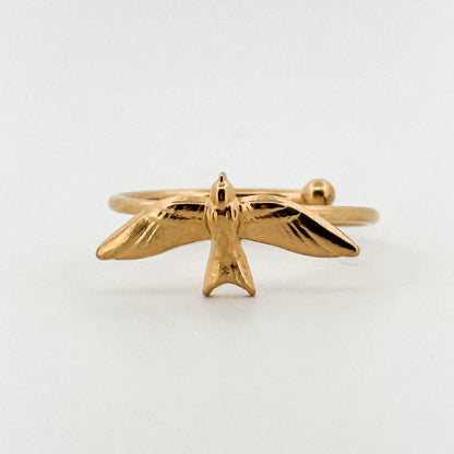 Gold bird-shaped ring on a light background