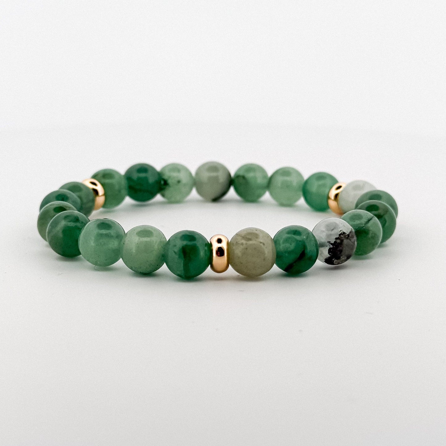 Green aventurine beaded bracelet with gold and silver accents on a light gray background