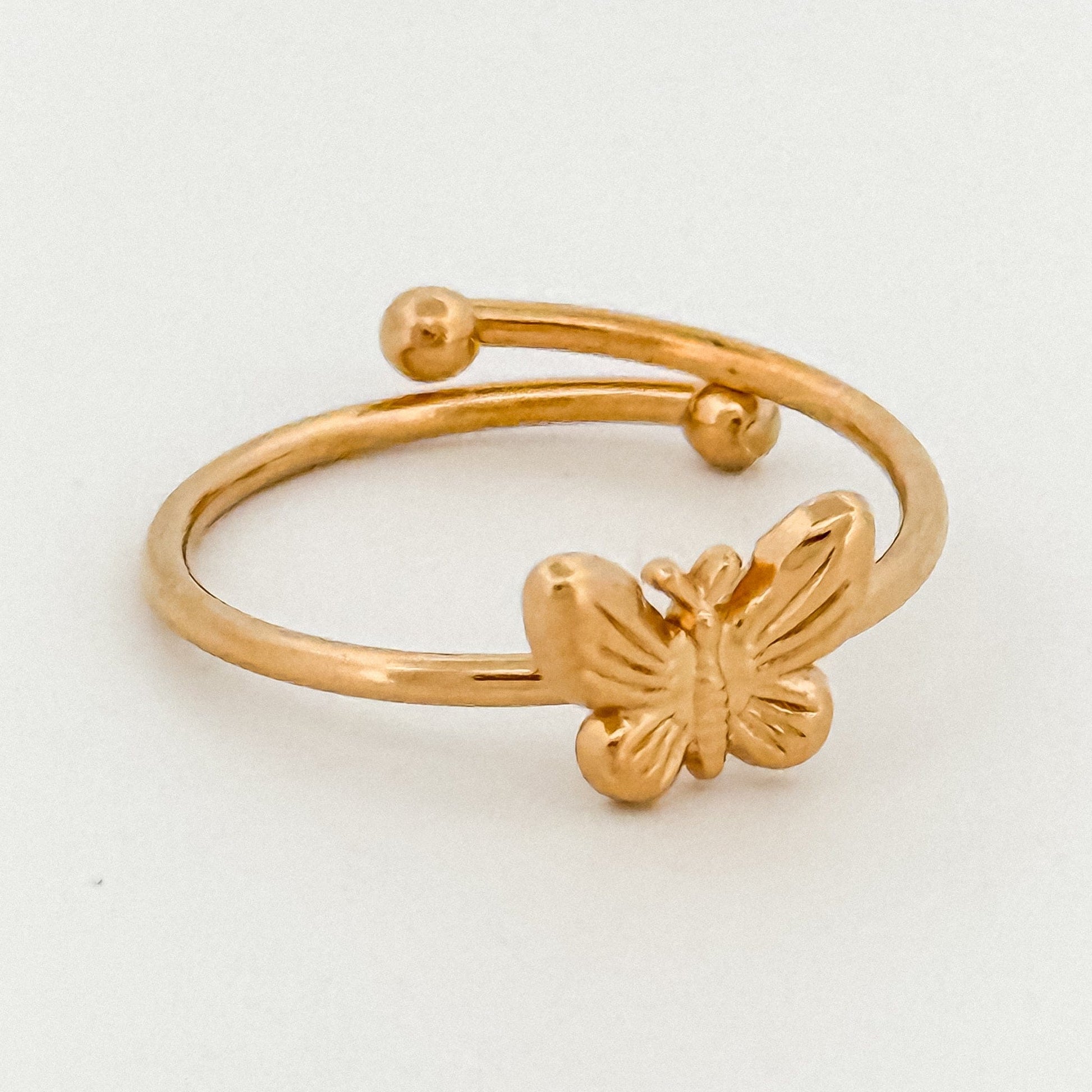 Gold butterfly ring on a light gray background