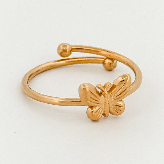 Gold butterfly ring on a light gray background