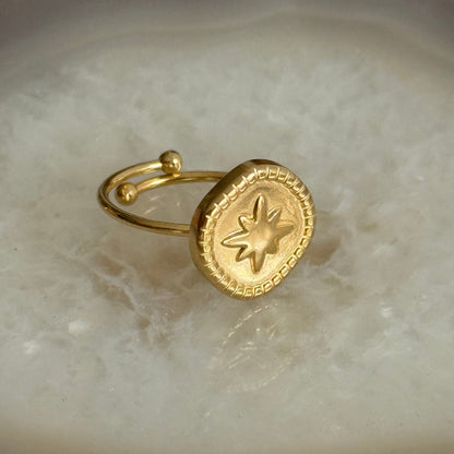 Gold ring with star design on a marble surface