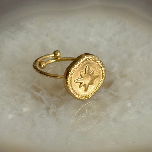 Gold ring with star design on a marble surface