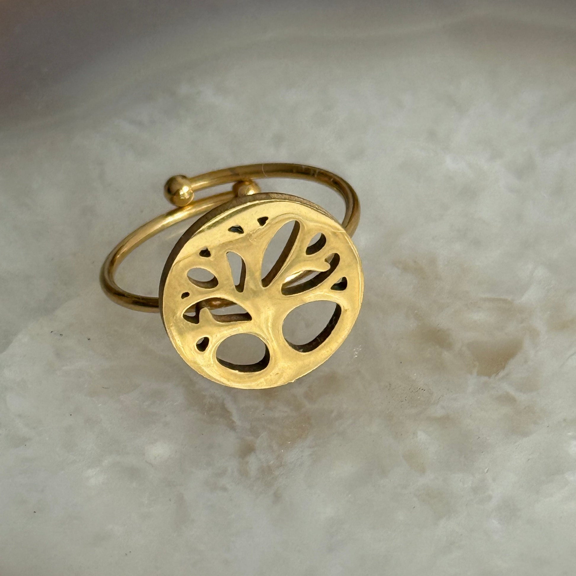 Gold ring with tree of life design on a marble surface
