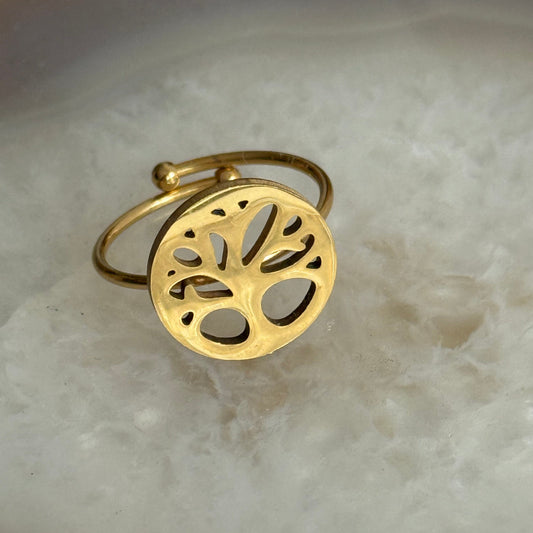 Gold ring with tree of life design on a marble surface