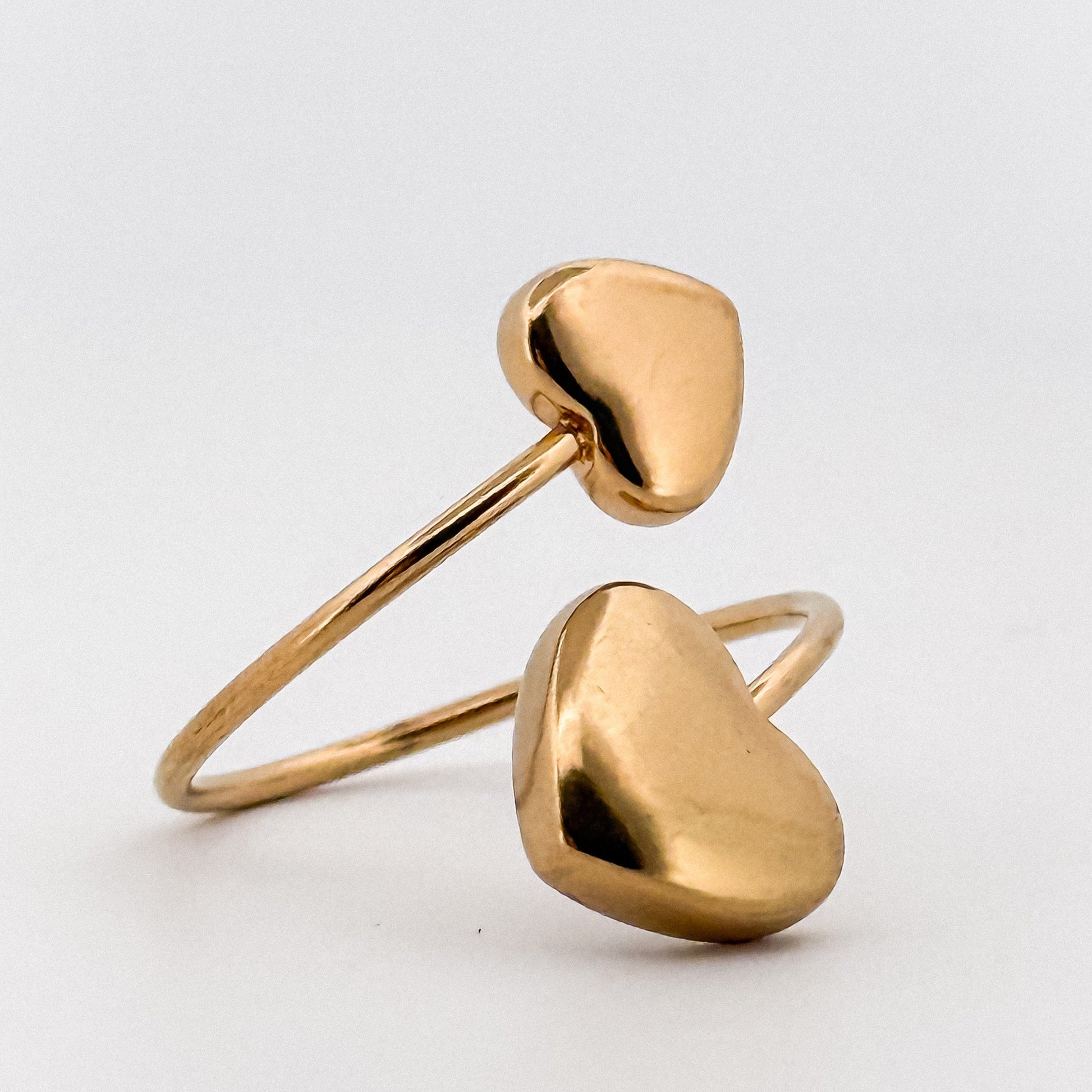 Gold open ring with two hearts, on a light gray background